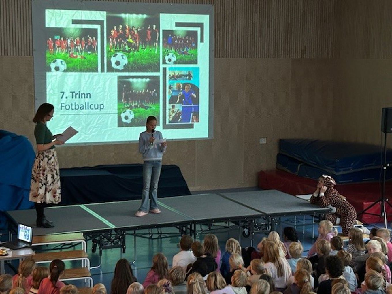 en person og person på scenen med en projektorskjerm og en folkemengde som ser på